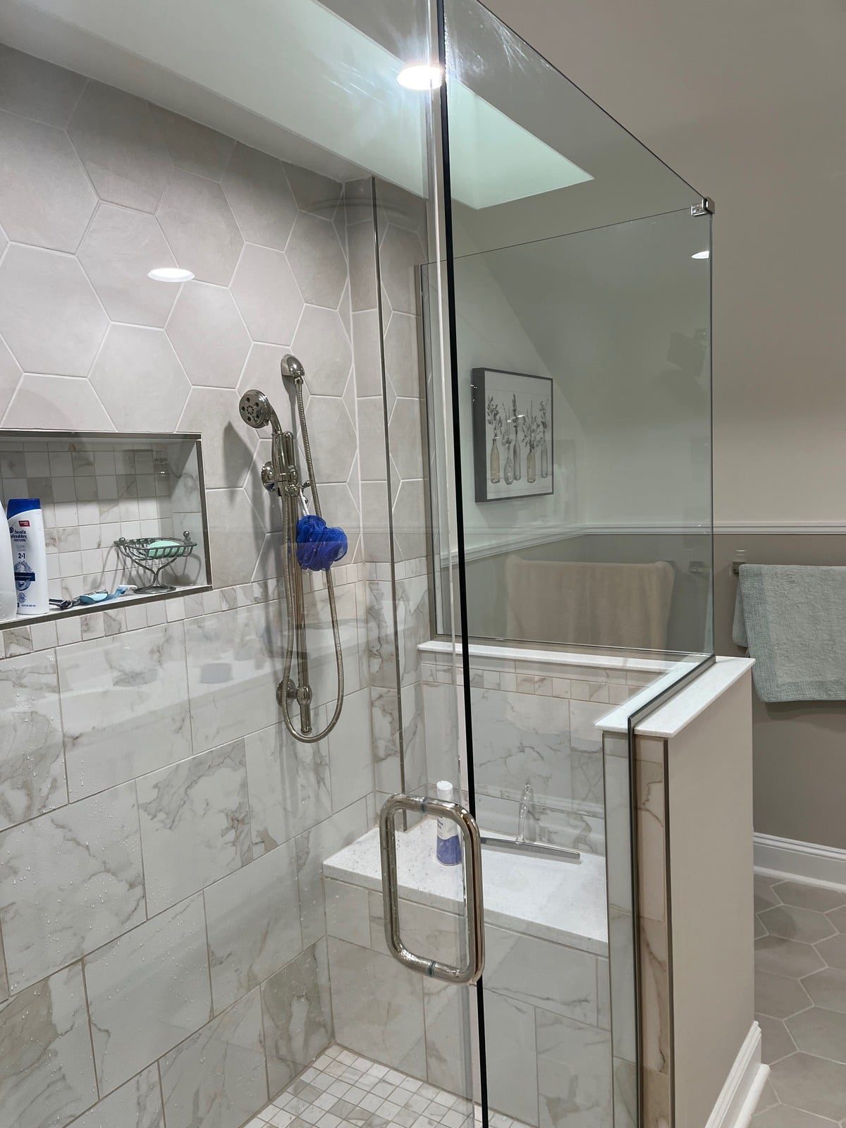 Glass shower enclosure with hexagon tile and marble accents
