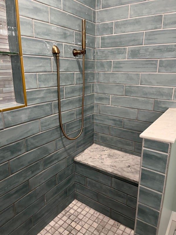 Gray tile shower with brass fixtures